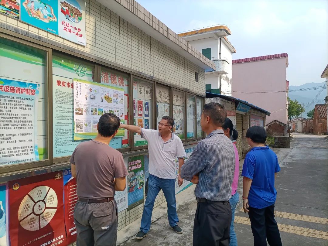 肇庆市鼎湖区沙浦镇桃二村委干部张贴“广东省村庄规划实用指南”宣传海报并向村民讲解海报内容.jpg